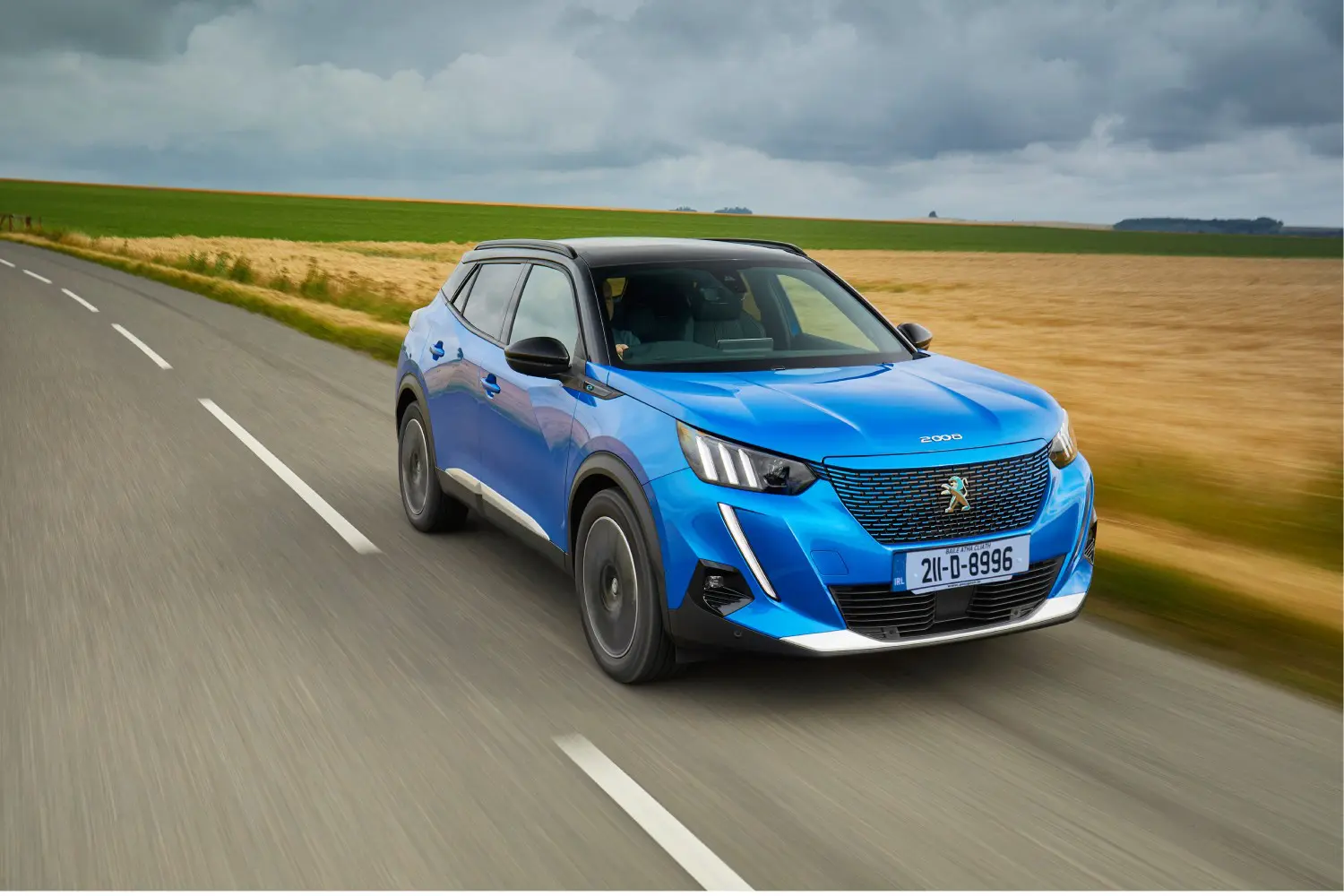 This is a photo of a Vertigo Blue Peugeot e2008 driving on a road.
