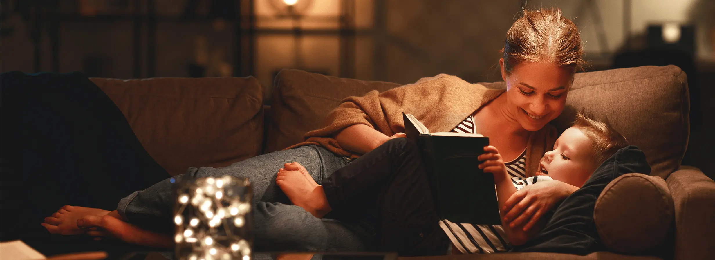 A woman & little boy reading a book on a couch