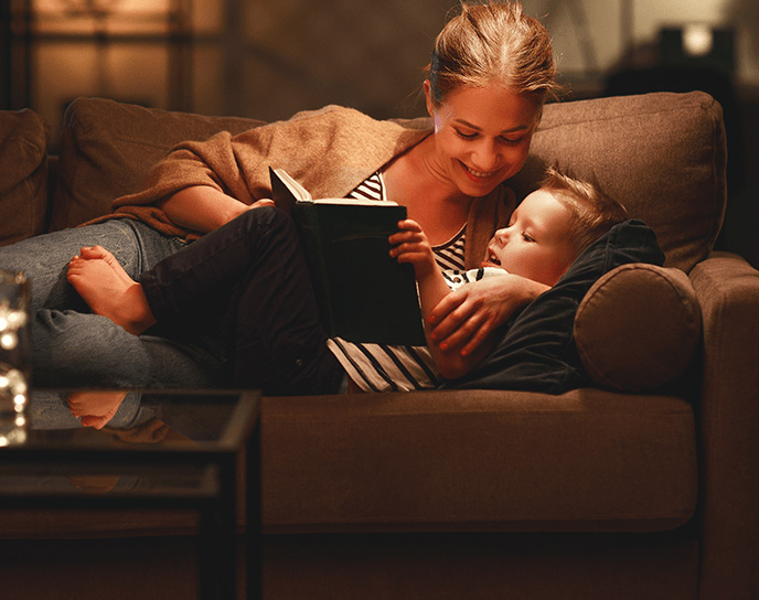 A woman & little boy reading a book on a couch